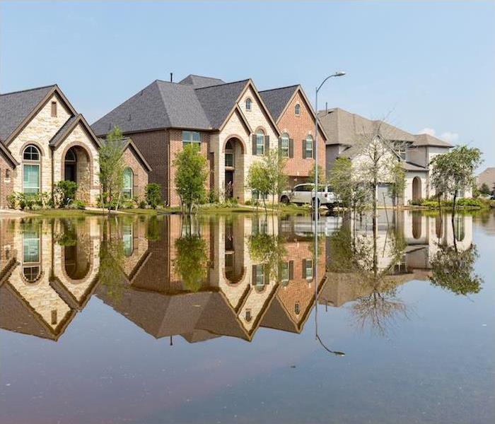 three large houses in a neighborhood with home and street flooded